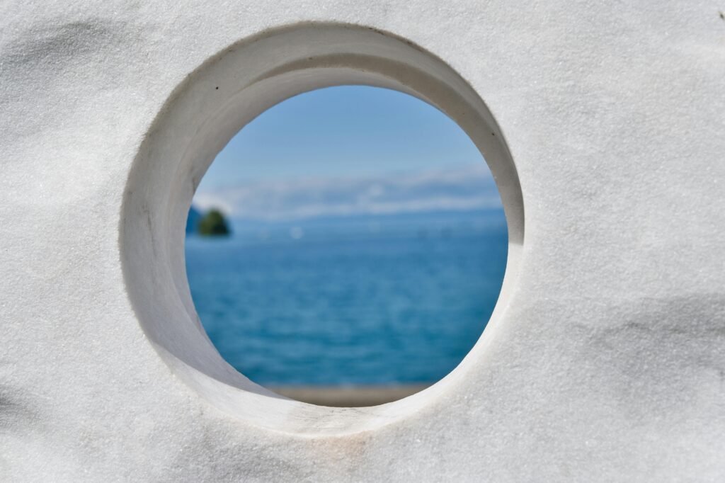A tranquil view of Lake Geneva framed by a stone circle, capturing the essence of Swiss elegance and calm waters.